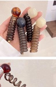 Close-up of spiral hair rings with glossy round beads in amber and brown shades