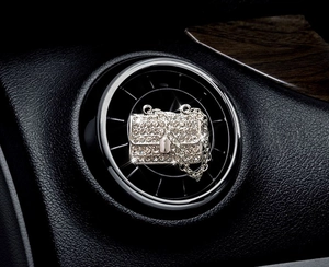 Macro shot of sparkling rhinestone-encrusted bag-shaped car air vent perfume clip