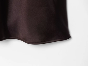Close-up of the elegant lace hem detail on a dark brown silk satin midi dress