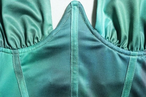 Detail of green gradient corset dress showing fishbone support and satin fabric texture