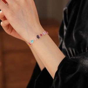 Detail of colorful gemstone bracelet featuring square and round cut crystals on silver chain