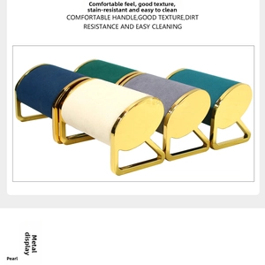 Detailed view of velvet watch and jewelry display pillows with gold metal supports