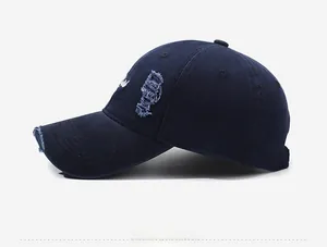 Close-up of side embroidery and distressed ripped details on a navy cotton baseball cap