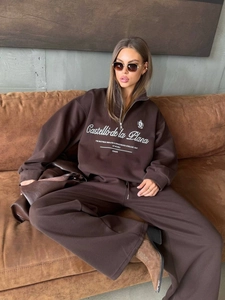 Detail of dark brown oversize half-zip sweatshirt set with white letter printing on chest