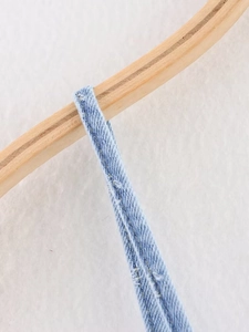 Dettaglio delle spalline regolabili su un abito in denim azzurro con cuciture rifinite