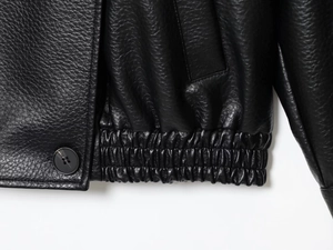 Makrodetail der schwarzen PU-Lederjacke mit Lychee-Narbenstruktur und elastischem Saum