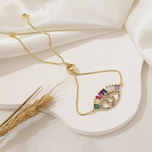 Adjustable gold evil eye bracelet with colorful zircons on a white display stand