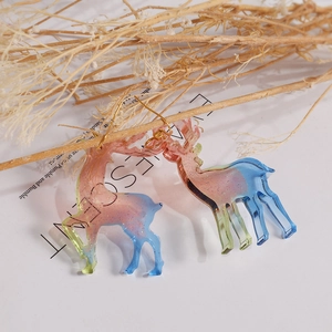 Detailed close-up of glitter resin reindeer earrings hanging on a natural tree branch