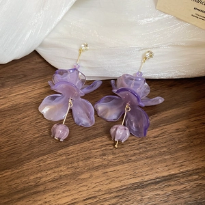 Detailed macro view of purple resin flower earrings with gold hooks and sparkling rhinestones