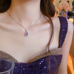 Close-up of elegant purple glass gourd pendant with sparkling zircon on necklace
