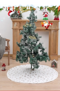 Detail of white plush Christmas tree skirt featuring golden embroidered snowflake patterns