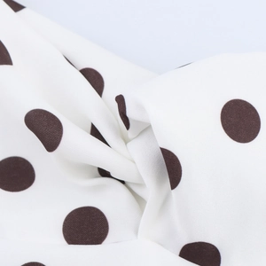 Gros plan d'une robe blanche à pois noirs avec un détail de nœud torsadé sur le tissu