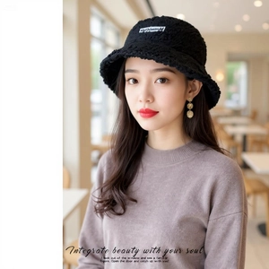 Detail of black lamb wool bucket hat with premium textured fabric and white woven label