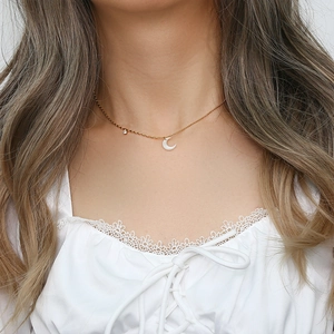 Detail shot of a crescent moon pendant necklace with gold chain on female model