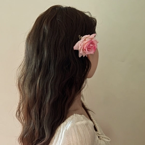 Close-up of pink fabric rose hair clip with gradient petals worn on model side hair