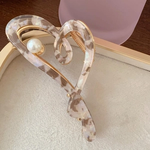 Detailed view of acetate shark hair clip with marble pattern and inlaid pearl accent