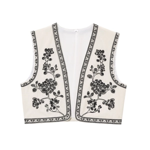 Gros plan du gilet sans manches beige avec broderie noire et tissu texturé détaillé