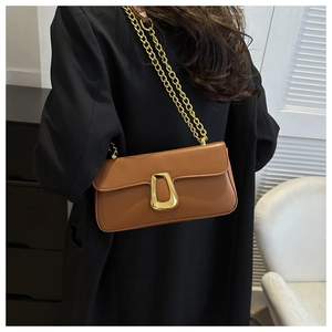 Close-up of brown chain square bag with golden trapezoid buckle on a model's shoulder