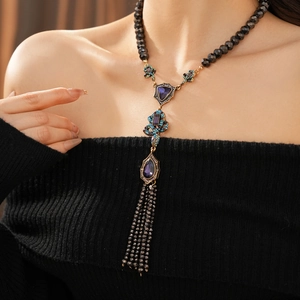 Gros plan détaillé du collier serpent vintage avec gemme violette et pompons en perles