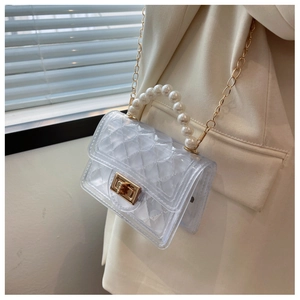 Detail of transparent PVC jelly bag with pearl handle and golden chain strap