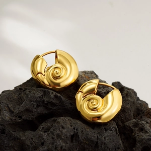 Detailed macro view of 18K gold-plated snail shell earrings on a black volcanic rock