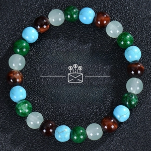 Detail of beaded wealth bracelet with tiger eye, citrine and malachite on black background