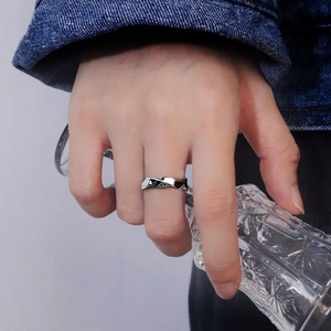 Silver Mobius ring with irregular wave design worn by a model holding a glass