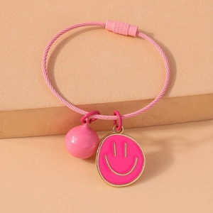 Detailed macro view of pink steel wire bracelet with gold-rimmed smiley face and ball charms