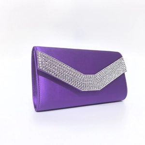 Close-up of purple satin evening clutch bag with sparkling V-shaped rhinestone trim detail