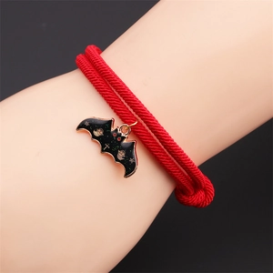 Close-up of red braided rope bracelet featuring a black enamel bat pendant for Halloween