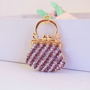 Golden purse keychain with purple and white rhinestones on a clean white surface
