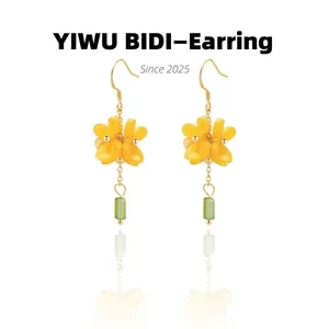 Detail of yellow flower drop earrings with a green crystal pendant on gold chain