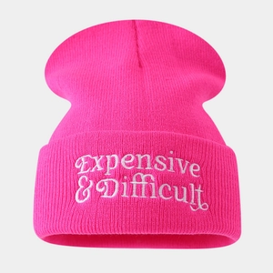 Close-up of pink knit beanie showing white Expensive and Difficult letter embroidery