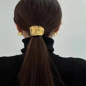 Detailed close-up of golden hammered lava hair clip and matching earrings on a model