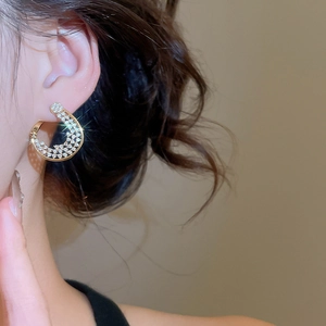 Gros plan d'un mannequin portant des créoles torsadées dorées 18K avec zircons pavés