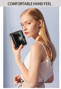 Close-up of model holding the black short leather wallet with stylish metal keychain