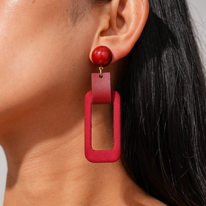 Detail of burgundy geometric drop earrings featuring layered leather and fabric textures