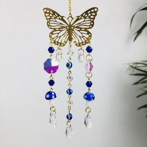 Detail of golden butterfly car charm with blue evil eye beads and crystal pendants