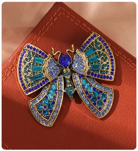 Close-up of vintage butterfly brooch with blue and teal rhinestones on leather surface