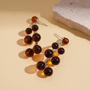 Macro shot of vintage resin bead drop earrings with amber stones on neutral stone base