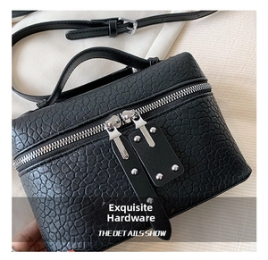 Detail view of black textured leather bag featuring silver dual zippers and rivet accents