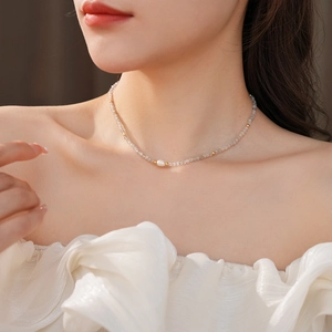Macro detail of a pearl and grey natural stone beaded necklace on a model collarbone