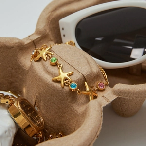 Detailed shot of gold starfish bracelet with multicolored zircons on a textured tray