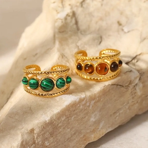 Dettaglio di anelli d'oro intrecciati con malachite verde e pietre occhio di tigre