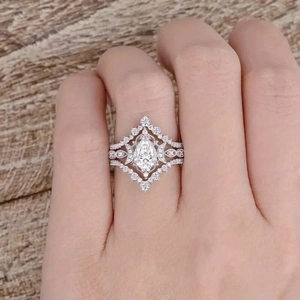 Close-up of a pear-shaped bridal ring set with sparkling stones on a person's finger