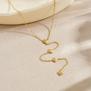 Elegant gold plated stainless steel necklace with four sparkling starburst pendants on sand
