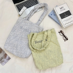 Detailed top view of plaid canvas tote bags with Sozalk print among lifestyle accessories