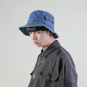 Blue denim bucket hat with decorative side pocket shown on model in studio lighting