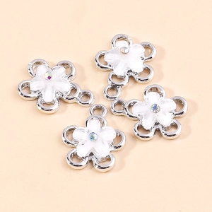 Close-up of white enamel flower pendants with sparkling aurora rhinestones and silver base