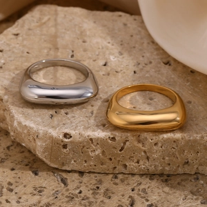 Polished stainless steel rectangular rings in gold and silver finish on a stone base